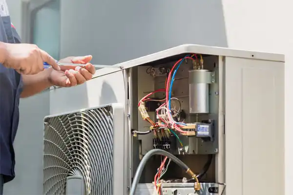 A technician uses a screwdriver to service an open air conditioning unit after the furnace won’t turn on.